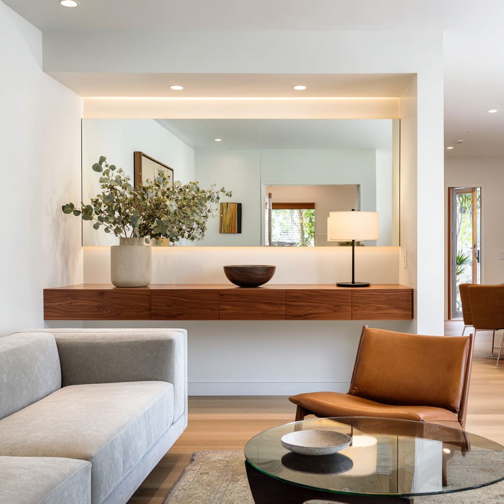 This composition places a wide, unframed mirror directly behind a floating walnut console, recessed into a niche that includes concealed perimeter LED This composition places a wide, unframed mirror directly behind a floating walnut console, recessed into a niche that includes concealed perimeter LED